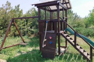 Деревянная детская площадка с качелями и брусьями на природе